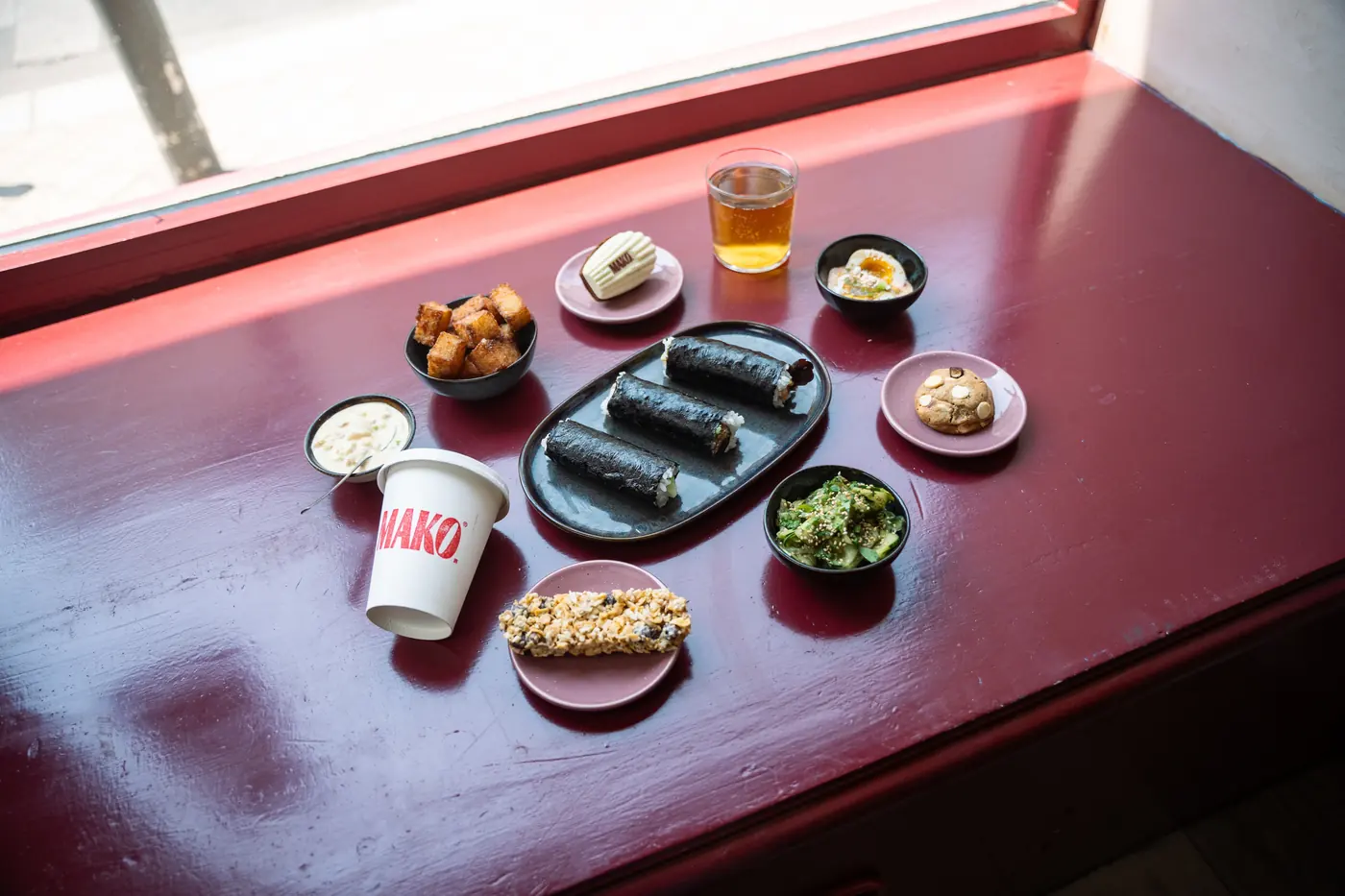 Rouleaux et petites assiettes servis chez Mako, sur une table rouge